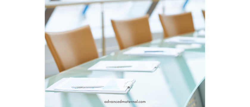 Image shows a conference table with notepads and pens and three chairs